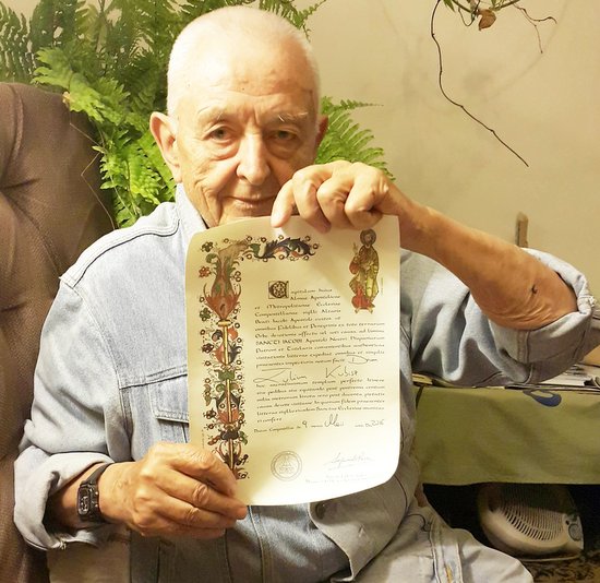 Doktor Juliusz Kubisz prezentuje certyfikat otrzymany po przejściu trasy pielgrzymki