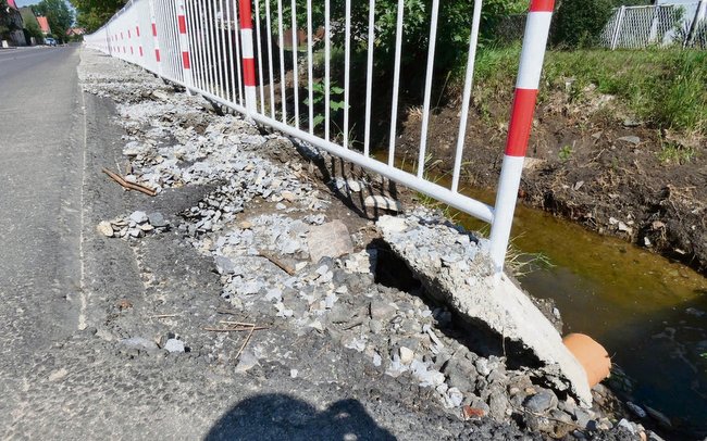 W centrum wsi fundament barierki ochronnej został tak podmyty, że aż się zsunął  w stronę potoku