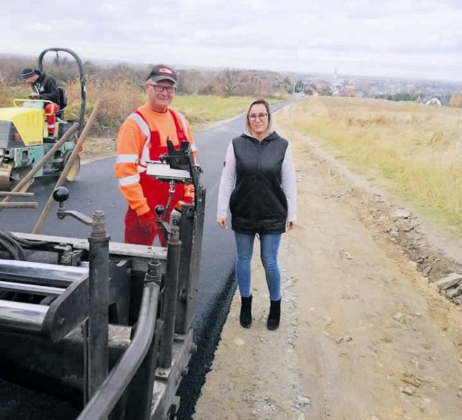 Na zdjęciu radna z Gęsińca Agnieszka Ruszek, która  jako jedna z kilku o tę inwestycję od dawna zabiegała. Obok pracownik firmy w trakcie kładzenia asfaltu